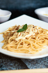 spaghetti with little tomato, using chopsticks, dark background