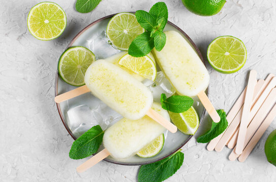 Refreshing Lime Popsicles, Brazilian Lemonade Ice Lolly with Fresh Lime and Mint on Bright Background