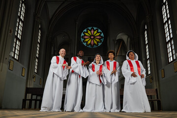 Group of people in white costumes singing in church choir they standing in old church and clapping...