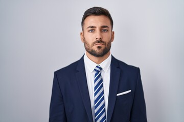 Handsome hispanic man wearing suit and tie relaxed with serious expression on face. simple and natural looking at the camera.