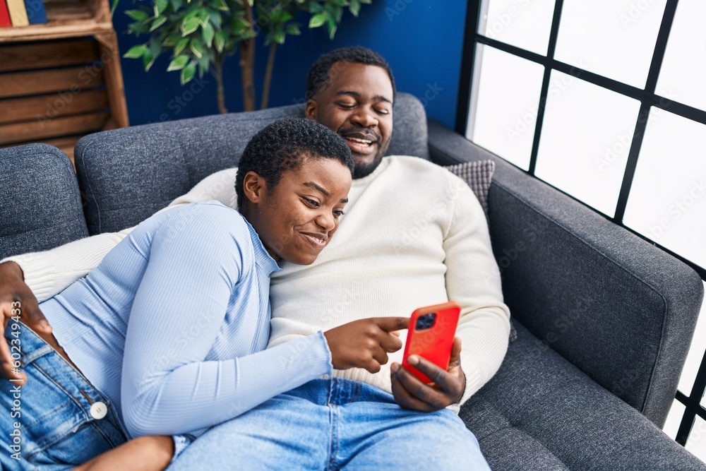 Sticker Man and woman couple using laptop lying on sofa at home