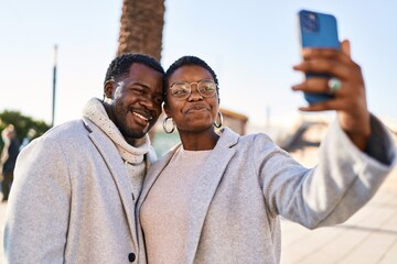 Man and woman couple standing together make selfie by the smartphone at street