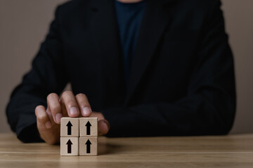 Businessman holding wooden cube with target board icon and arrow on wooden table. Goals and planning for success in marketing business, achieve the objective concept. Closeup and free copy space