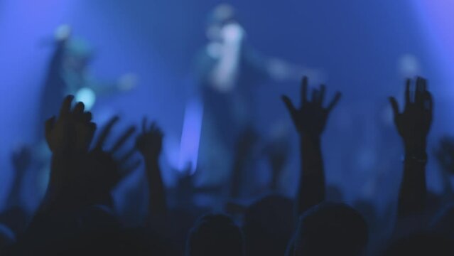 People swing their arms to the sides at a live concert