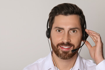 Hotline operator with headset on light grey background, space for text