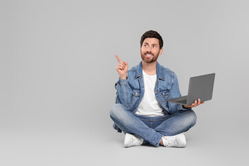 Happy man with laptop on light grey background. Space for text
