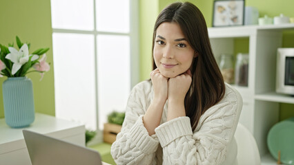 Young beautiful hispanic woman using laptop sitting on table at home