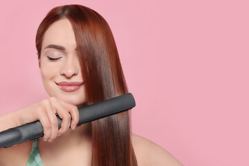Beautiful woman using hair iron on pink background, space for text