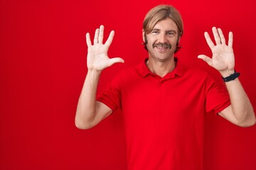 Caucasian man with mustache standing over red background showing and pointing up with fingers number ten while smiling confident and happy.