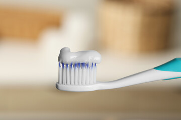 Plastic toothbrush with paste on blurred background, closeup