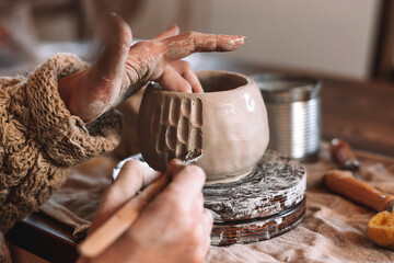 Female sculptor making clay mug in a home workshop,hands close-up.Small...