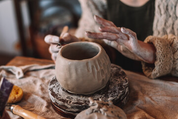 Female sculptor making clay mug in a home workshop,hands close-up.Small...
