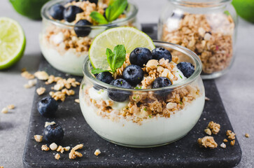 Crunchy Granola with Yogurt, Lime and Blueberries, Dessert Parfait, Healthy Snack or Breakfast on Bright Background