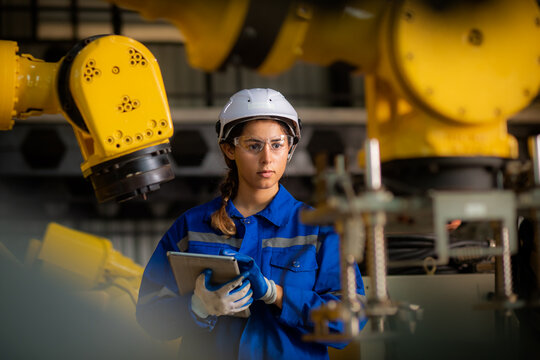 Caucasian female engineer, technician wearing safety uniform working use tablet Online information to monitor machine operation, check  maintenance plan to make a machine work efficiently and safely. - Powered by Adobe