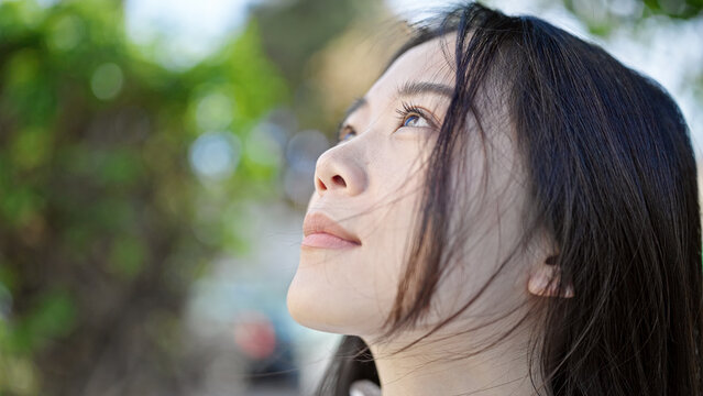 Young chinese woman looking to the sky with serious expression at park