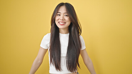 Young chinese woman smiling confident standing over isolated yellow background