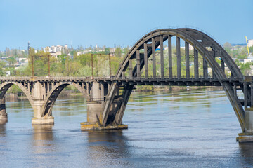 View of river Dnepr and railway ancient arched bridge. Unique construction across wide water 19th century. Railway line along the Merefo-Kherson bridge. Panoramic on modern city and spring landscape.