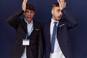 Two hispanic business men wearing business clothes surprised with hand on head for mistake, remember error. forgot, bad memory concept.