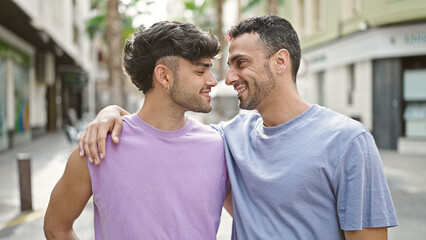 Two men couple smiling confident hugging each other at street