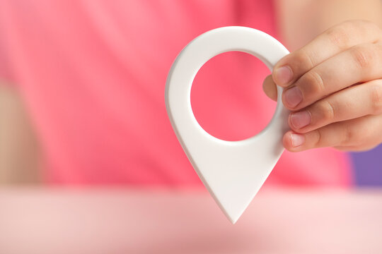 A hand holds a location sign on a purple background. Laying a route, finding the location of a point on the map. Pin icon sign or navigation map locator travel GPS direction pointer. - Powered by Adobe