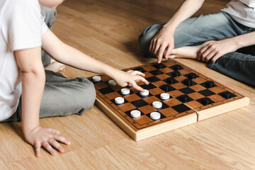two brothers in white T-shirts are lying on the floor and playing chess. early development....
