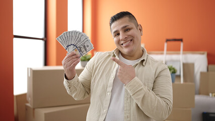 Young hispanic man smiling confident pointing to money at new home