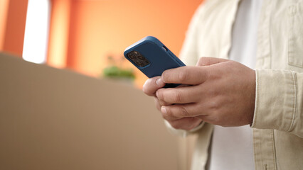 Young hispanic man using smartphone standing at new home