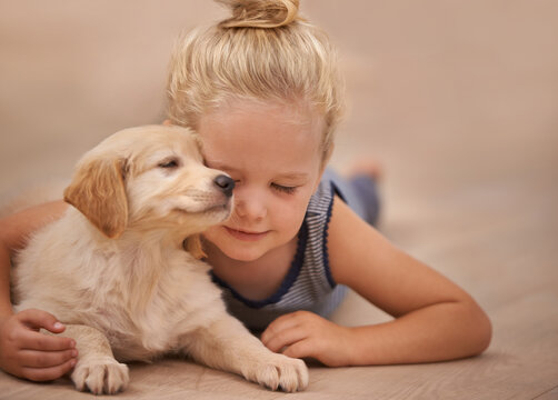 Young girl hug her dog, relax with peace and calm at home with golden retriever puppy and child. Mans best friend, pet care and love with female kid and her domestic animal lying on wood floor