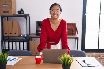 Young chinese woman business worker smiling confident standing by desk at office