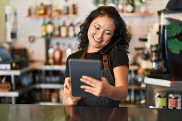 Young chinese woman waitress smiling confident using touchpad at restaurant