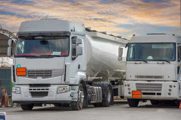 White fuel trucks in the parking lot at the petrol station.
