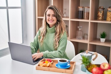 Obraz na płótnie Canvas Young woman using smartphone having breakfast at home