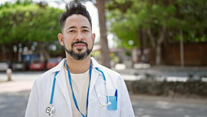 Young latin man doctor standing with relaxed expression at park