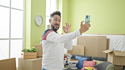 Obraz na płótnie Canvas Young latin man smiling confident having video call at new home