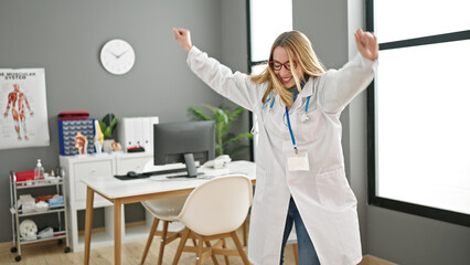 Young blonde woman doctor smiling confident dancing at clinic