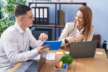 Man and woman business workers using laptop and touchpad working at office