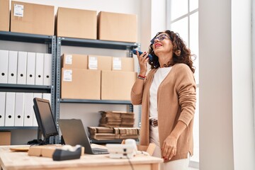 Middle age hispanic woman working sending voice message at ecommerce