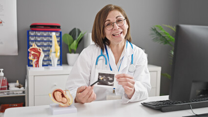 Middle age hispanic woman doctor showing ultrasound at clinic