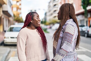 African american women friends standing together speaking at street