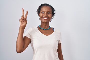 African woman with dreadlocks standing over white background showing and pointing up with fingers number two while smiling confident and happy.