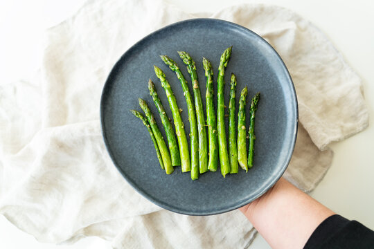 Close-up on a large plate - asparagus with salt and garlic. Delicious and healthy food served in a restaurant, beautifully served by the chef.
