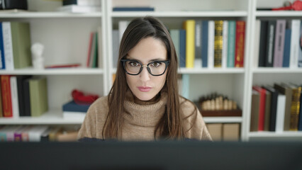 Beautiful hispanic woman student using computer studying at library university