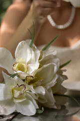 Wedding bouquet of the bride. The bride in a white necklace sits at the table and drinks coffee.