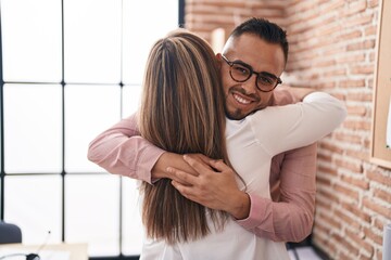 Man and woman business workers hugging each other at office