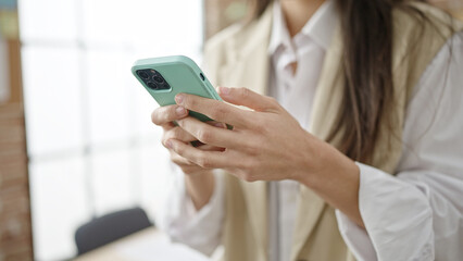 Young beautiful hispanic woman using smartphone at office