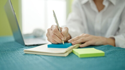 Young beautiful hispanic woman using laptop writing on reminder color stick at dinning room