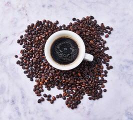  One cup of espresso and coffee beans on porcelain surface