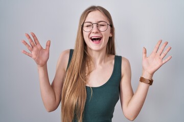 Young caucasian woman standing over white background celebrating mad and crazy for success with arms raised and closed eyes screaming excited. winner concept