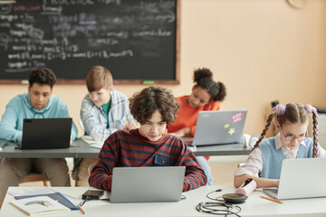 Group of school children using laptops in class during programming lesson