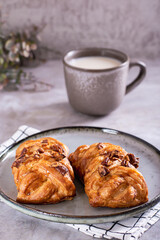 Wicker buns with cinnamon, nuts and maple syrup and a cup of coffee for Swedish fika time vertical